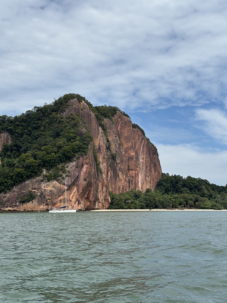 Båd langt væk på vandet med en klippe i baggrunden, Borneo, Malaysia