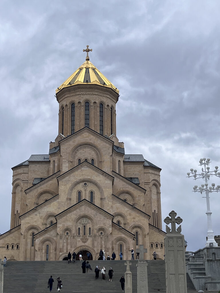 Den imponerende Holy Trinity Katedral (Sameba) i Tbilisi med sin store guldkuppel set fra trapperne mod en overskyet sky