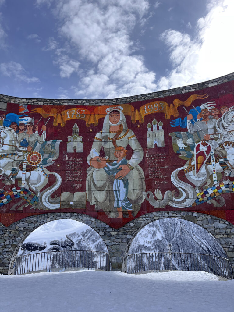 Buestrukturen på det ikoniske monument i Gudauri med farverige vægmosaikker og udkigsposter mod det sneklædte bjerglandskab